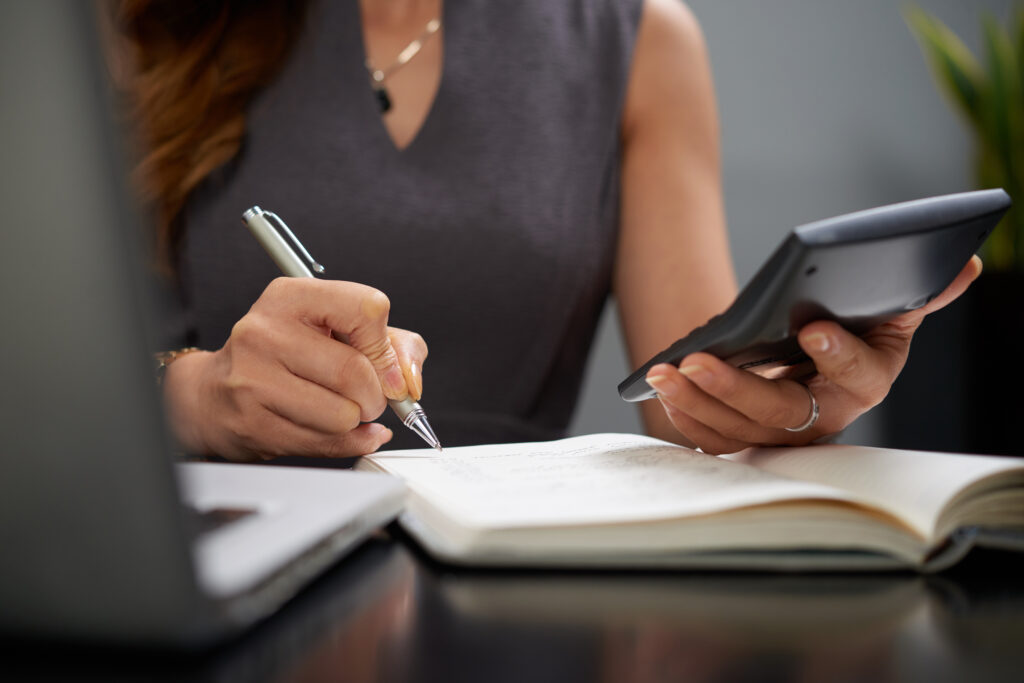Mujer revisando sus finanzas con calculadora, bolígrafo y papeles — ahorro y gestión de dinero para principiantes